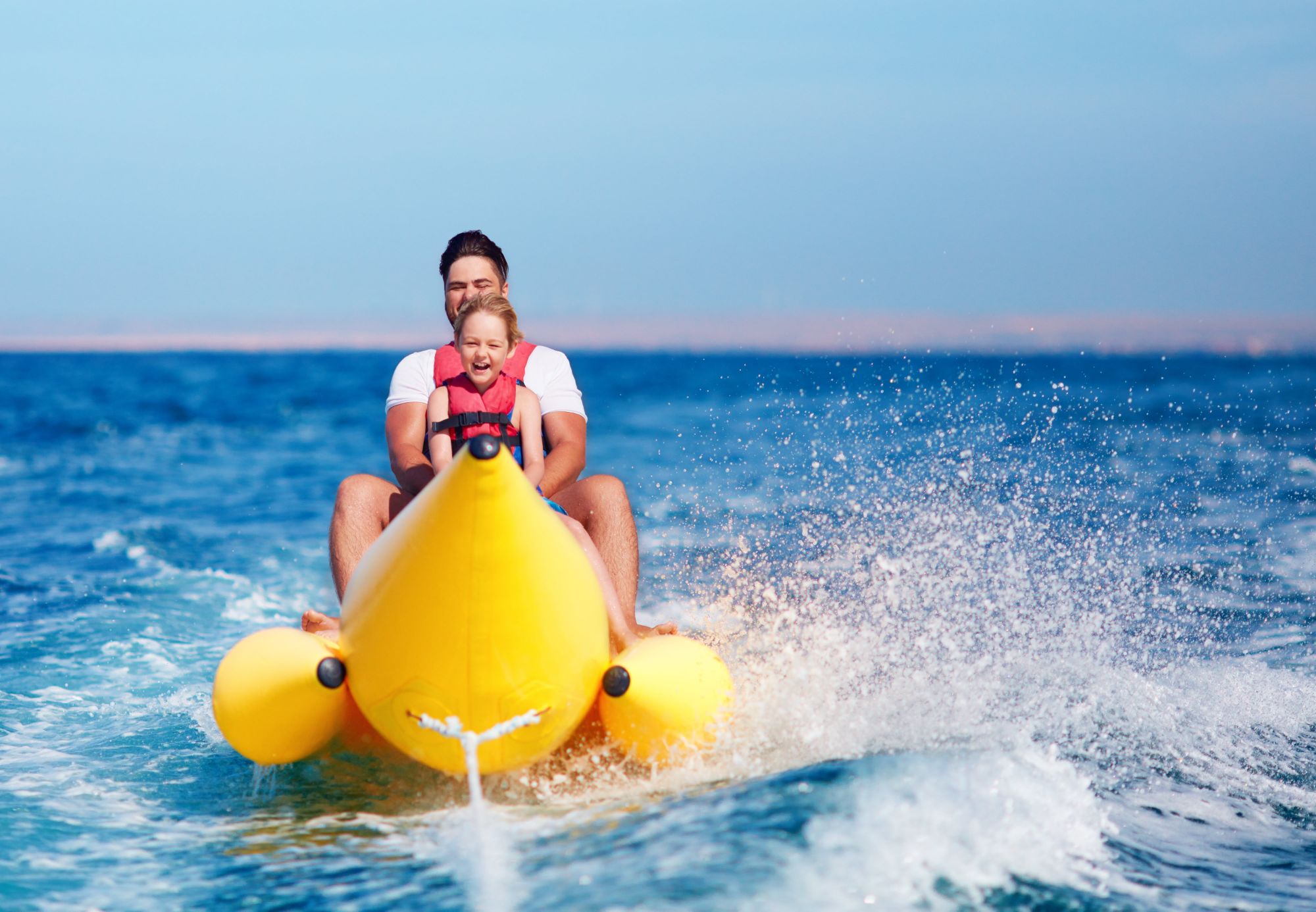 Father and daughter riding a banana boat